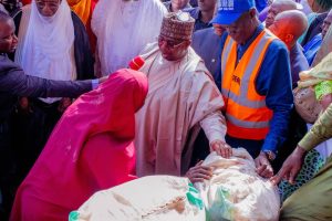 Kebbi State Governor Dr. Nasir Idris giving out food items to a victim of the flood at the IDPs camp